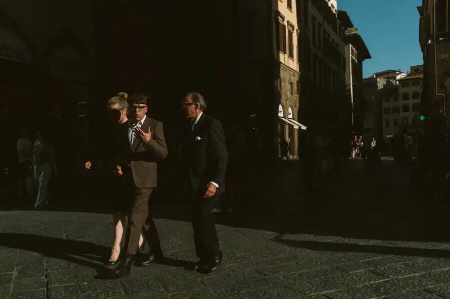 Two elegant men walking on the street in Italy beside an elegant woman